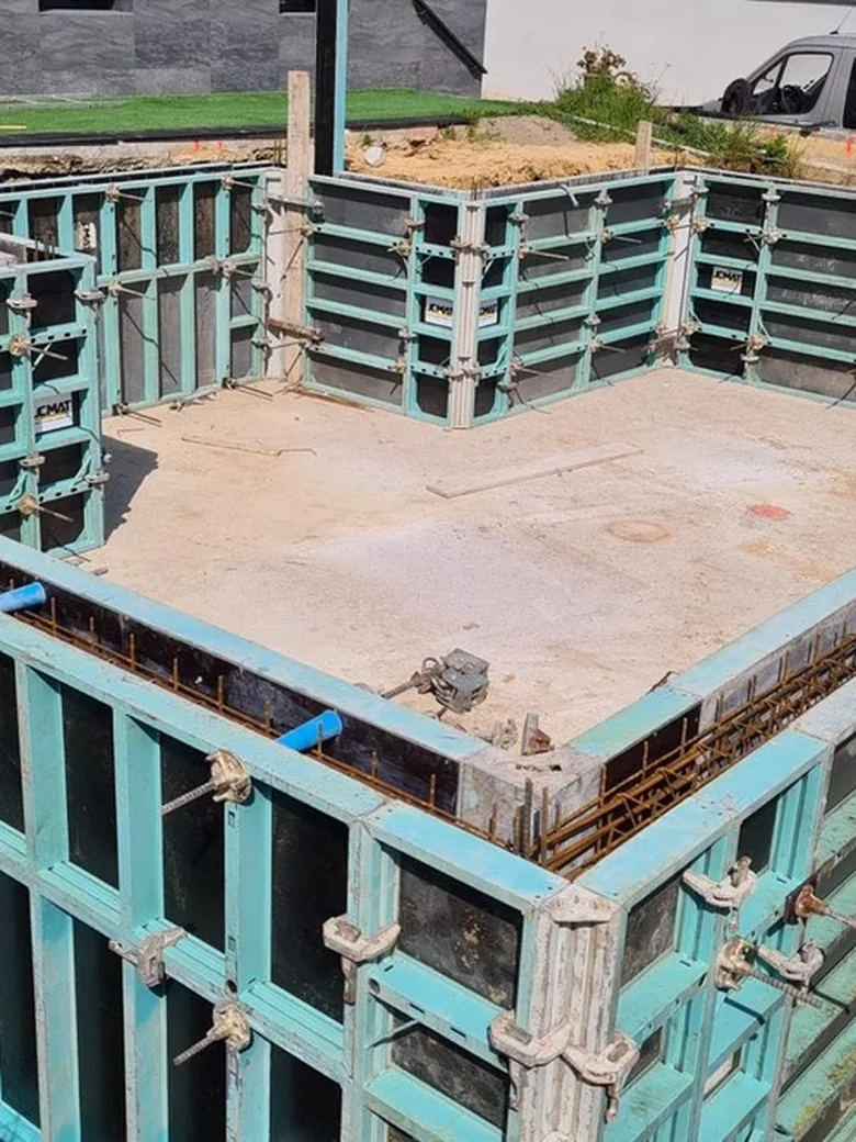 Coffrages métalliques dressés autour d'un bassin en construction.