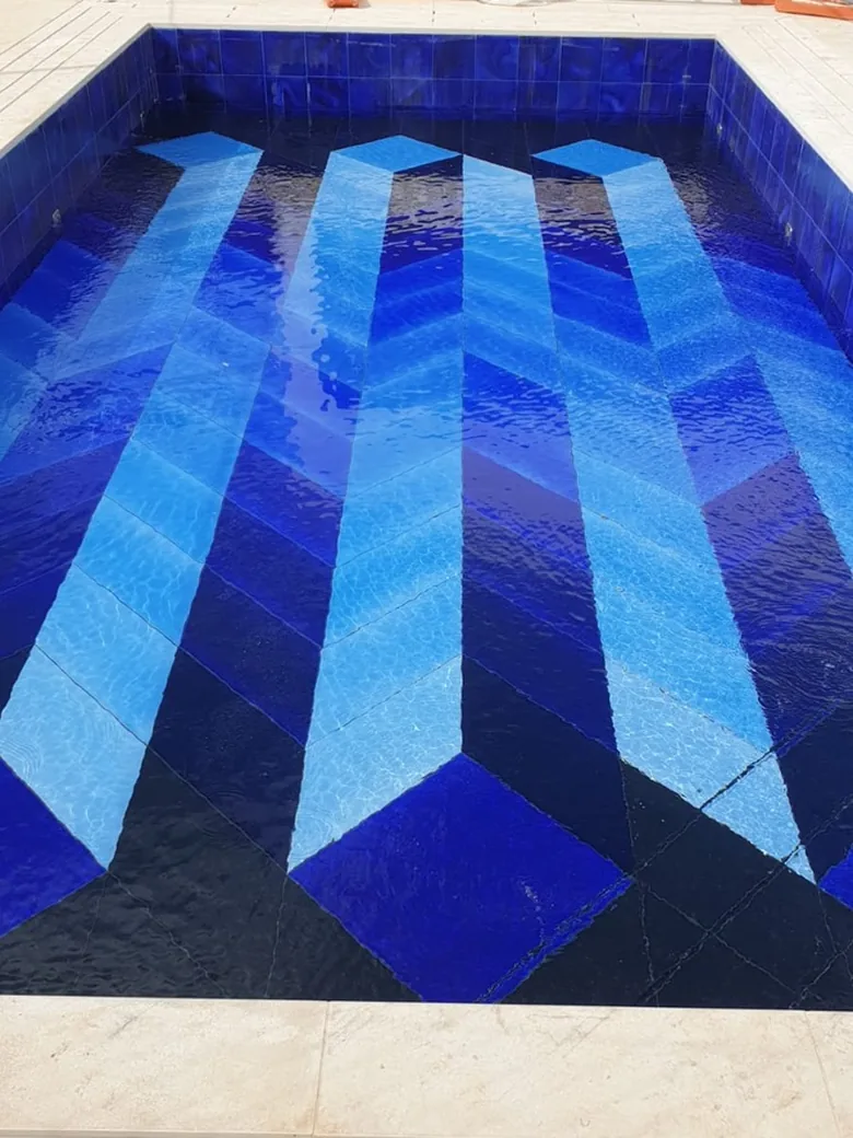 Fond de bassin carrelé en mosaïque bleue, bassin en cours de remplissage.