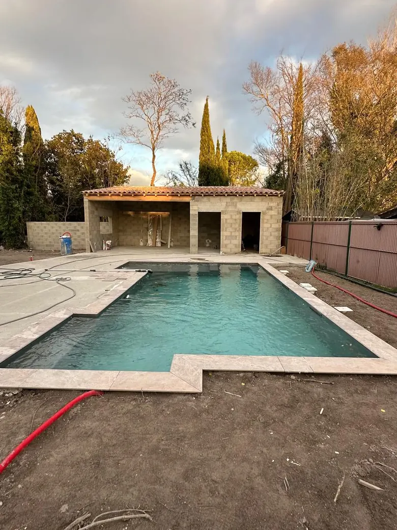 Bassin rempli devant un pool house, abords encore en terre.